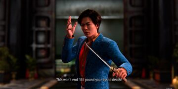 Captura de pantalla de "Like A Dragon Gaiden" mostrando a un personaje masculino en una chaqueta azul con patrones, en una pose de combate con una espada, con una expresión decidida. El fondo es un interior borroso que parece un dojo o una sala tradicional japonesa. Un subtítulo en inglés dice: "This won't end 'til I pound your ass to death!", reflejando la intensidad y crudeza del diálogo del juego. La imagen transmite la acción y el drama intensos que caracterizan a esta serie de juegos.