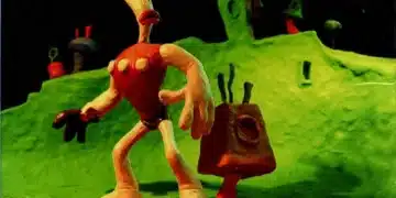 Capa do jogo 'The Neverhood', destacando uma figura de massinha vermelha e branca em um cenário verde e surreal. O título 'The Neverhood Cheat Codes' sugere um guia para truques dentro deste mundo de aventura em argila