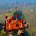 Captura de pantalla de Lego Fortnite mostrando una estructura flotante de ladrillos Lego con globos rojos sobre un paisaje virtual verde con árboles y lagos, bajo un cielo azul claro.