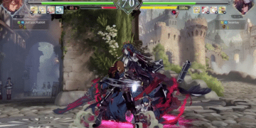Captura de pantalla del juego "Granblue Fantasy Versus: Rising" mostrando un vibrante combate en un escenario medieval con dos personajes en un duelo intenso. Un luchador desata un poderoso ataque especial contra su oponente, rodeado de efectos visuales espectaculares y detalles enérgicos. La interfaz del juego muestra las barras de vida, tiempo y un medidor de habilidades especiales lleno, indicando un momento crítico en la batalla. La escena se desarrolla ante la mirada de espectadores en un ambiente detallado que evoca la rica narrativa y el mundo de "Granblue Fantasy".