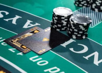 Uma mão de cartas de blackjack revelando um Ás de espadas, acompanhada por fichas de cassino empilhadas sobre o feltro verde da mesa de jogo