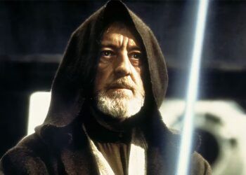 Alec Guinness como Obi-Wan Kenobi en 'Star Wars: Episodio IV', con capucha y sable de luz encendido, reflejando sabiduría y una profunda seriedad en su mirada