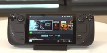 A high-resolution image of a Steam Deck OLED console displayed on a wooden table, surrounded by gaming accessories including a Steam-branded mug, a candle, and a controller. The Steam Deck OLED screen shows a vibrant game scene, highlighting its superior display quality.