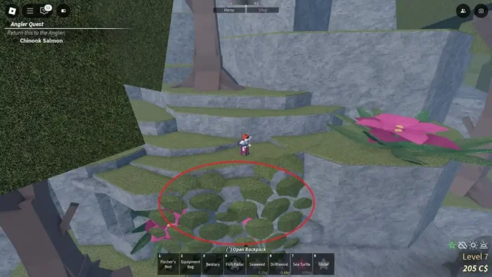 A player stands on a grassy ledge along the stone cliffs of Ancient Isle in Roblox Fisch, with large circular moss-covered stones arranged in a ring below, marked by a red circle, next to vibrant pink flowers and stylized blocky trees.