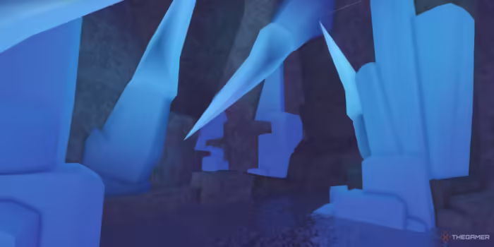 A glowing cave interior in Roblox Fisch's Northern Expedition, featuring large jagged blue crystal formations protruding from rocky cavern walls and ceilings, with reflections shimmering on the cave’s dark water floor.
